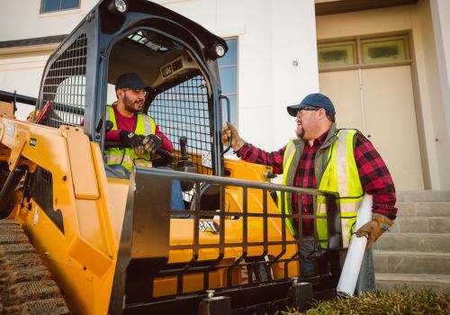 Guys talking by a skid steer CAT