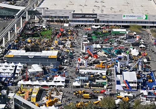 Aerial view of an CONEXPO-CON/AGG expo with booths, tents, heavy machinery, and crowds
